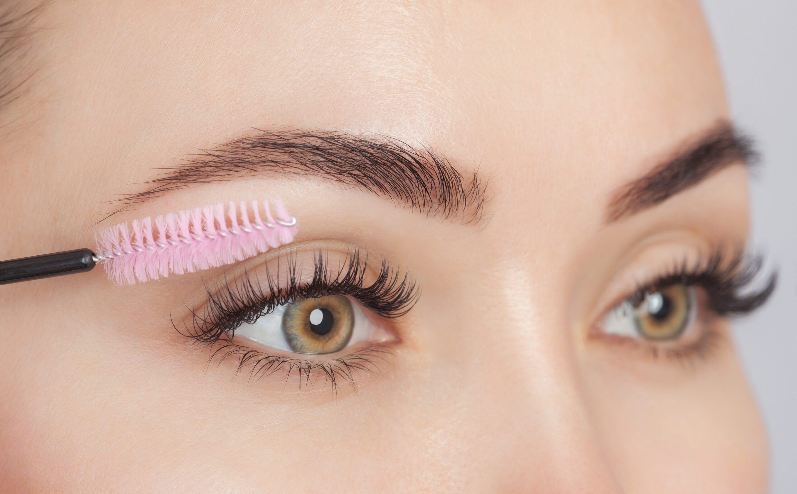 Woman with lash extensions and pink lash brush