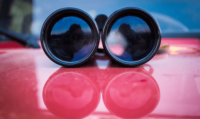 A set of binoculars on a red car