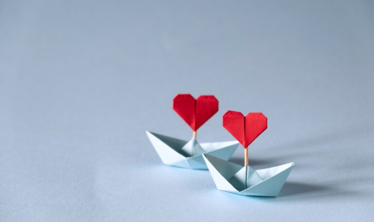 Origami boat with heart flag on glitter blue background 