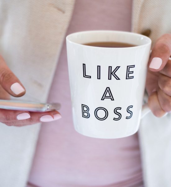 Business woman using mobile phone and holding cup that says Like